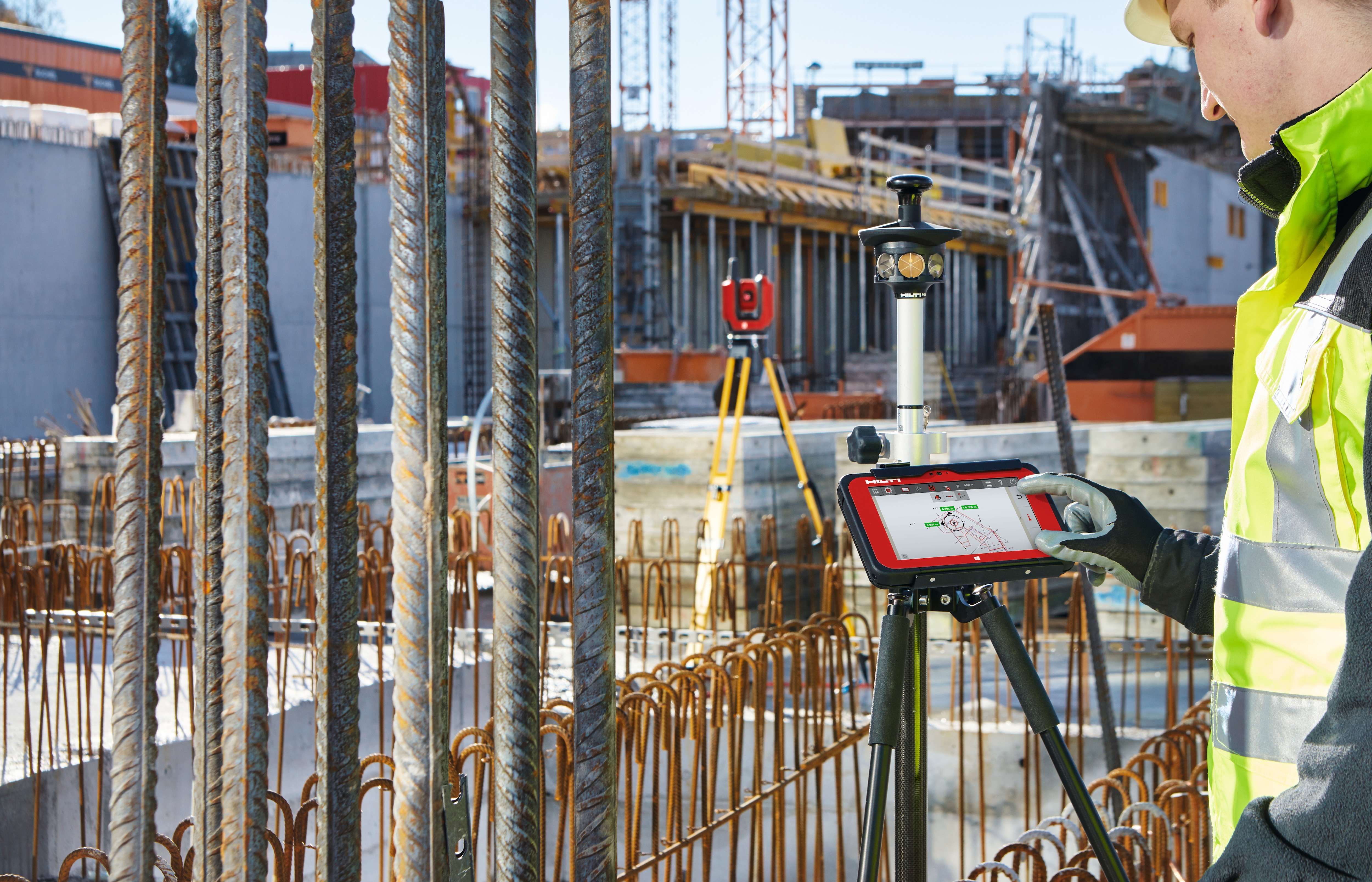 Man in yellow high visibility vest using red Hilti screen paired with Hilti red laser.