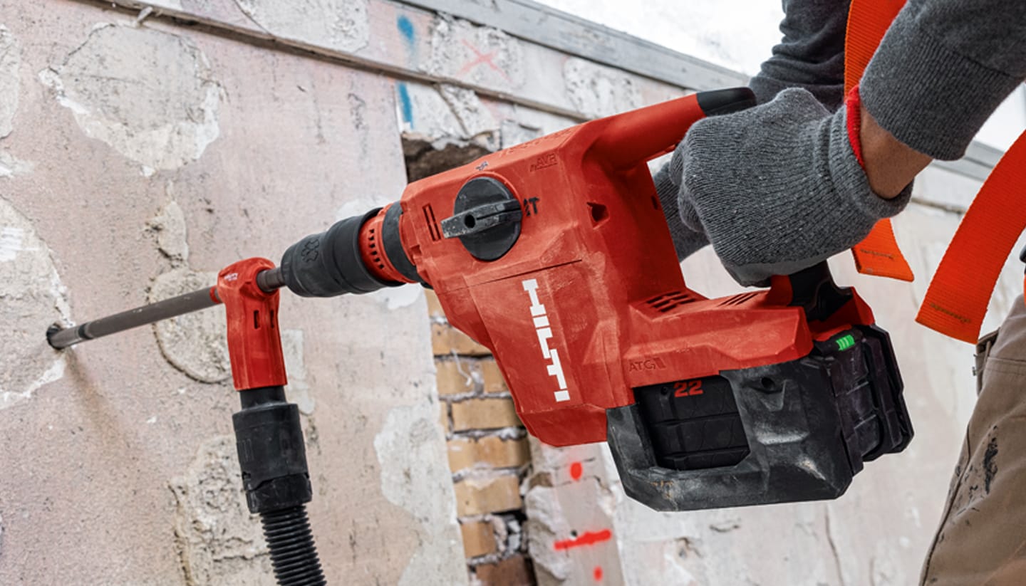 A PERSON USING A RED POWER DRILL TO DRILL HOLES