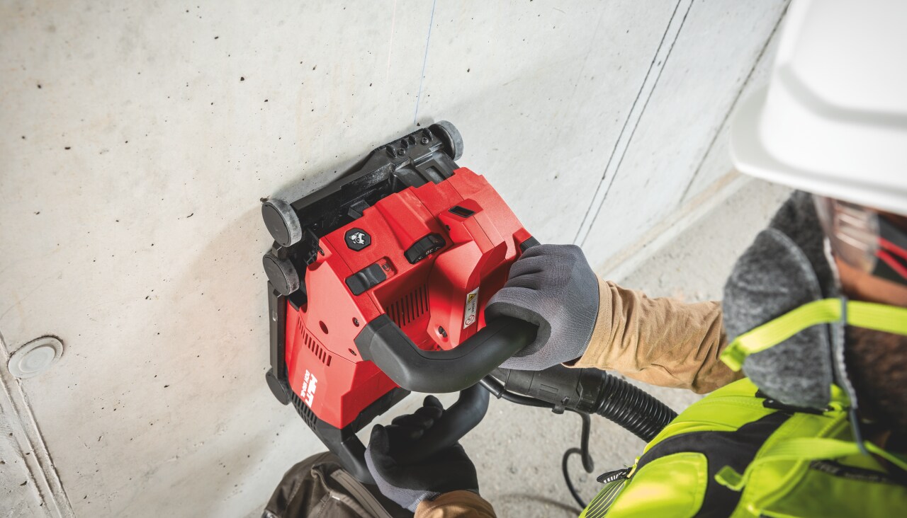 Construction worker in yellow high visibility vest and with respirator using Hilti red Wall Chaser.