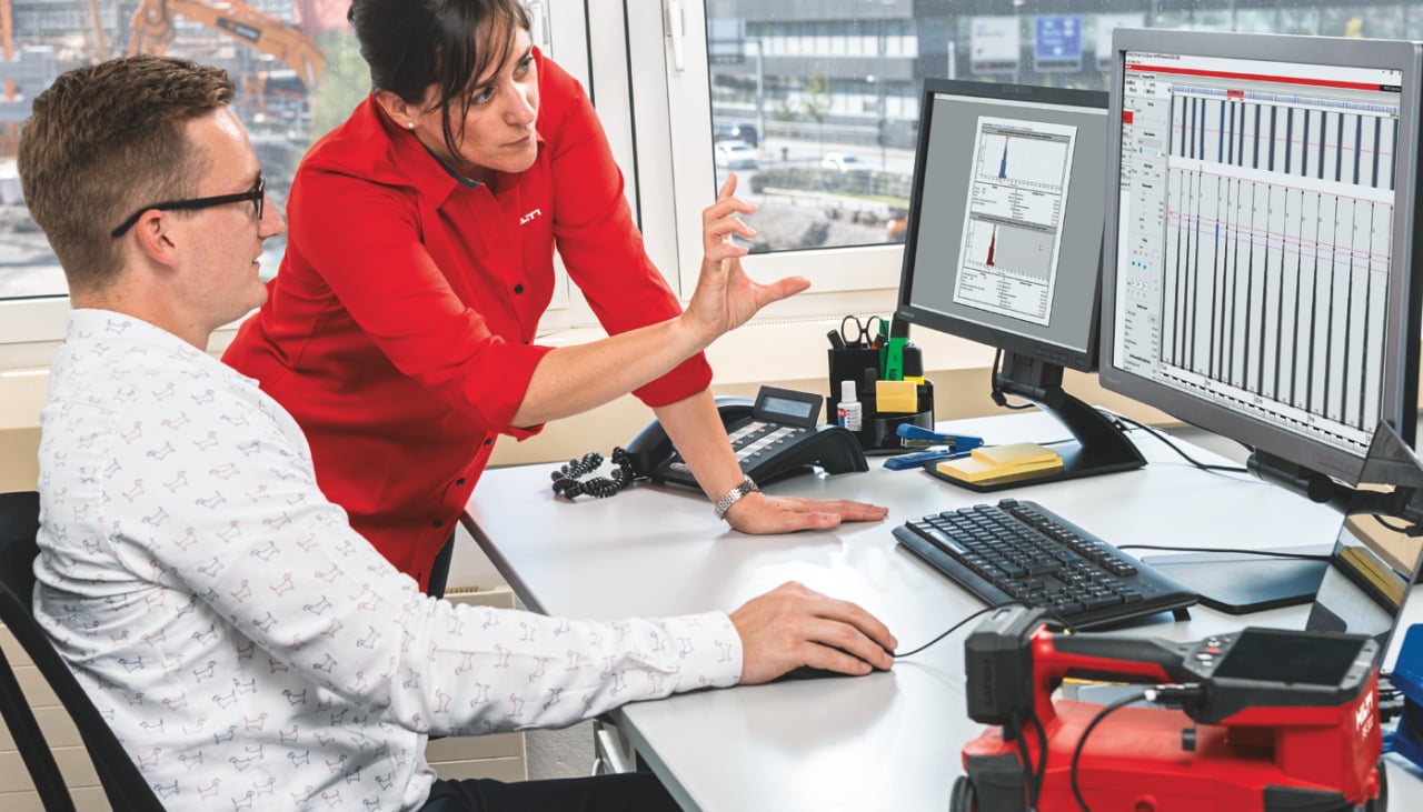 Man and a woman having a chat in the office, while watching pc screen with construction software. 