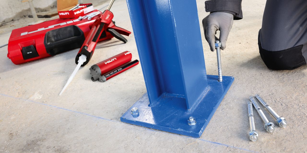 Man working on installation of metal anchor into concrete floor.
