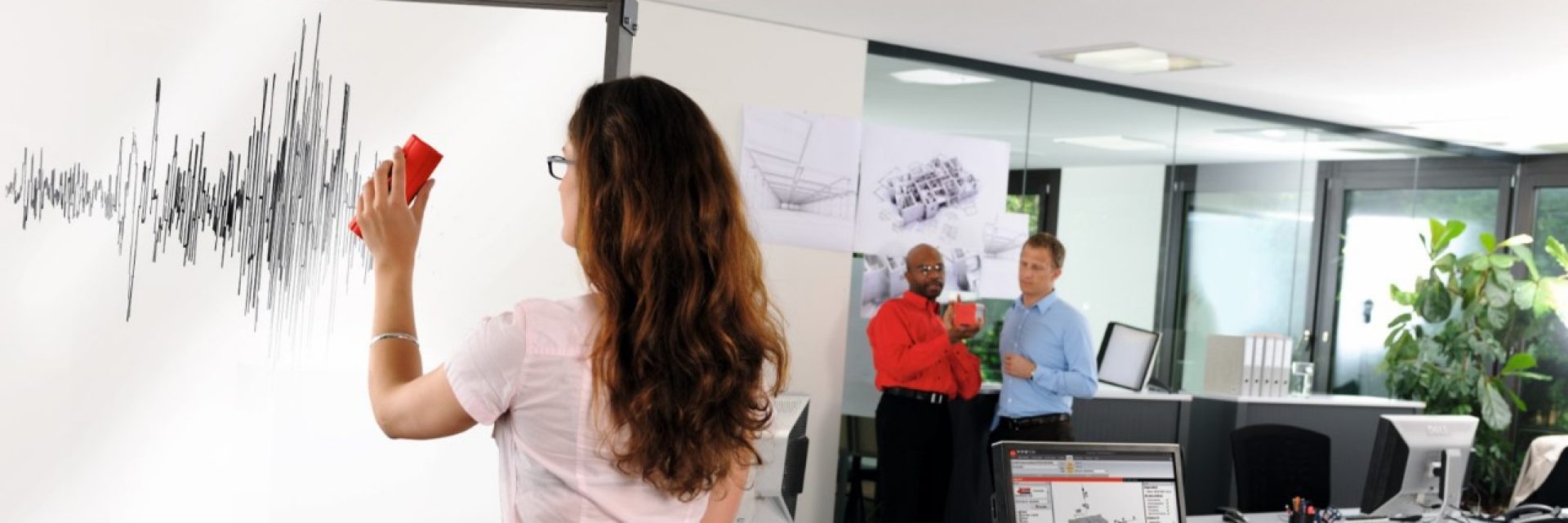 Woman controlling seismic chart in the office together with two men.