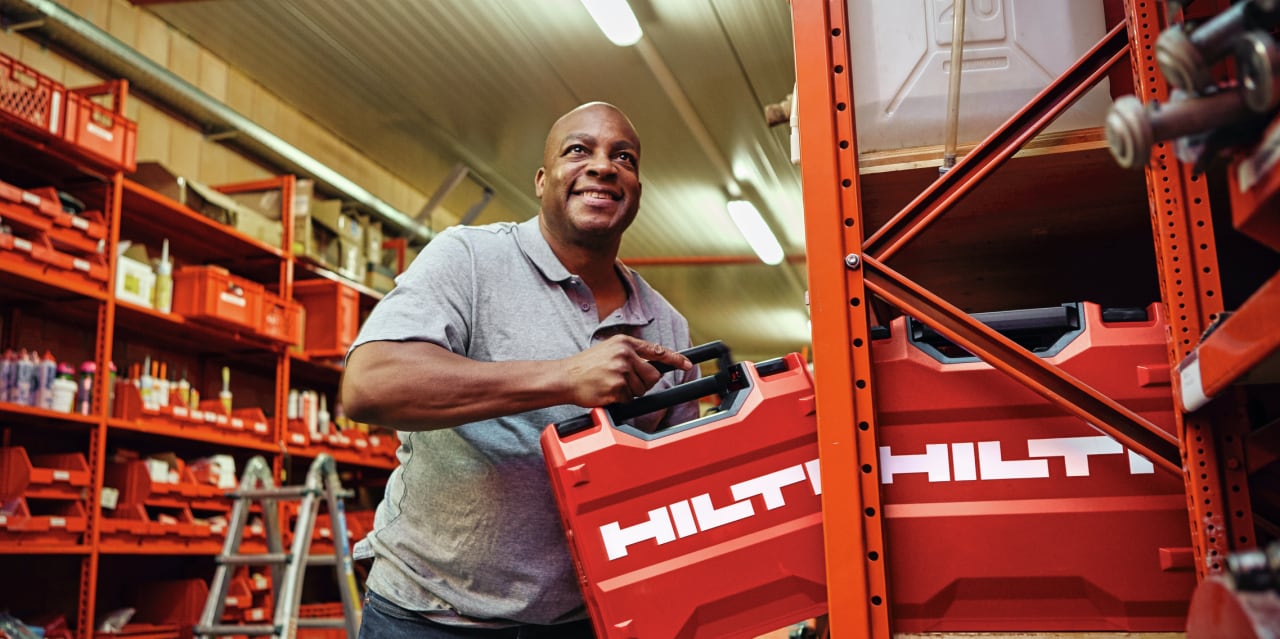 A man picking up Hilti red tools box from a warehouse