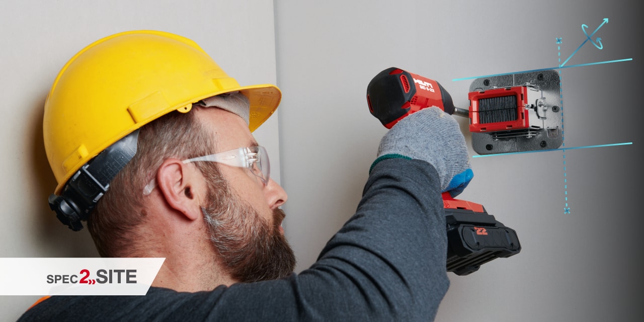 a worker uses a cordless driver to install a firestop device to a wall