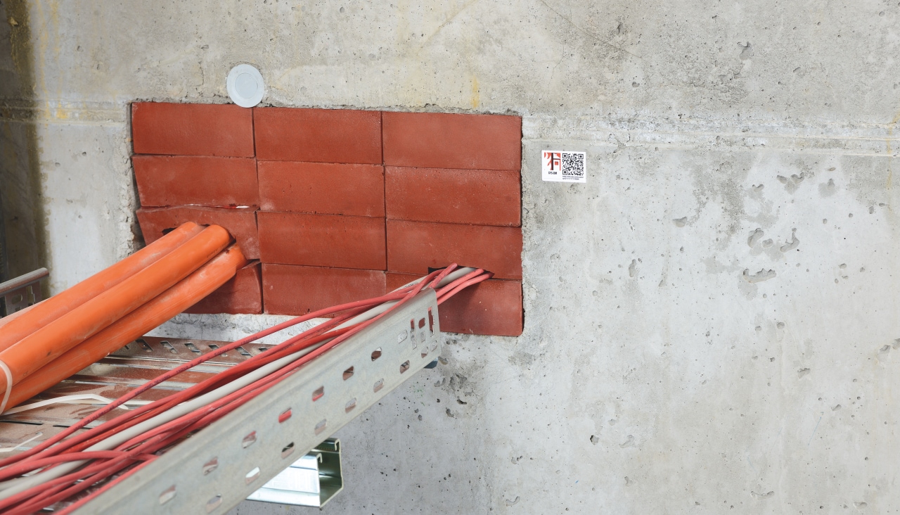 Cables and pipes are going through a wall and are fully isolated by Hilti firestop bricks.