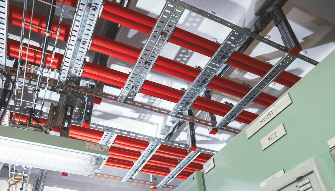Cable tray and ladder support metal construction, holding pipes and cables at the ceiling.