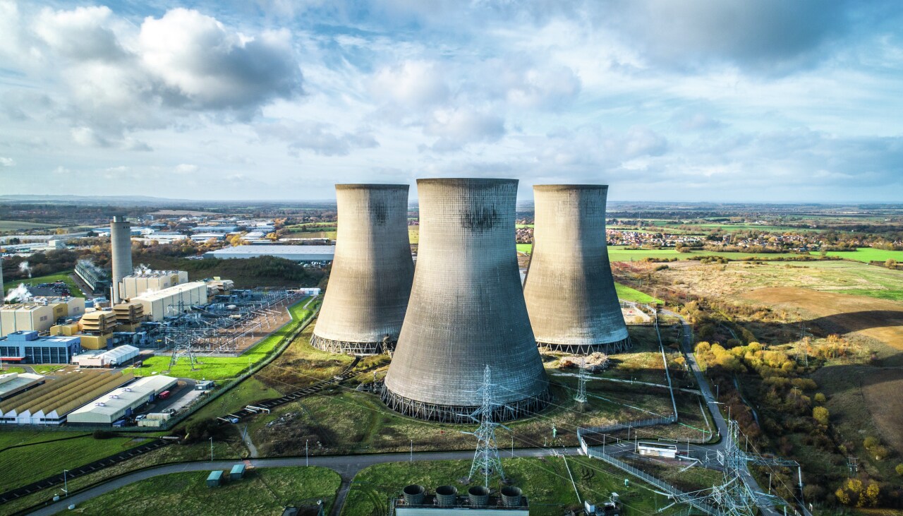Nuclear power plant with three towers located in green grass area.