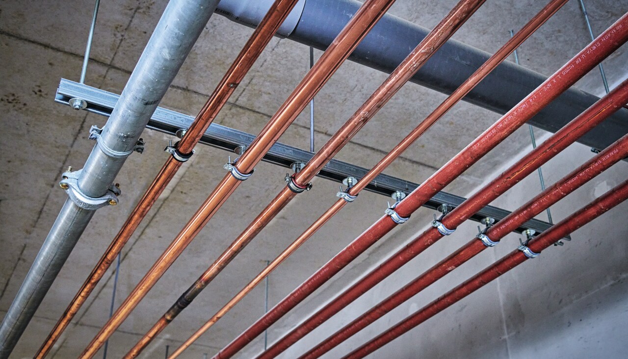 Metal construction supporting pipes close to ceiling in a power plant room.