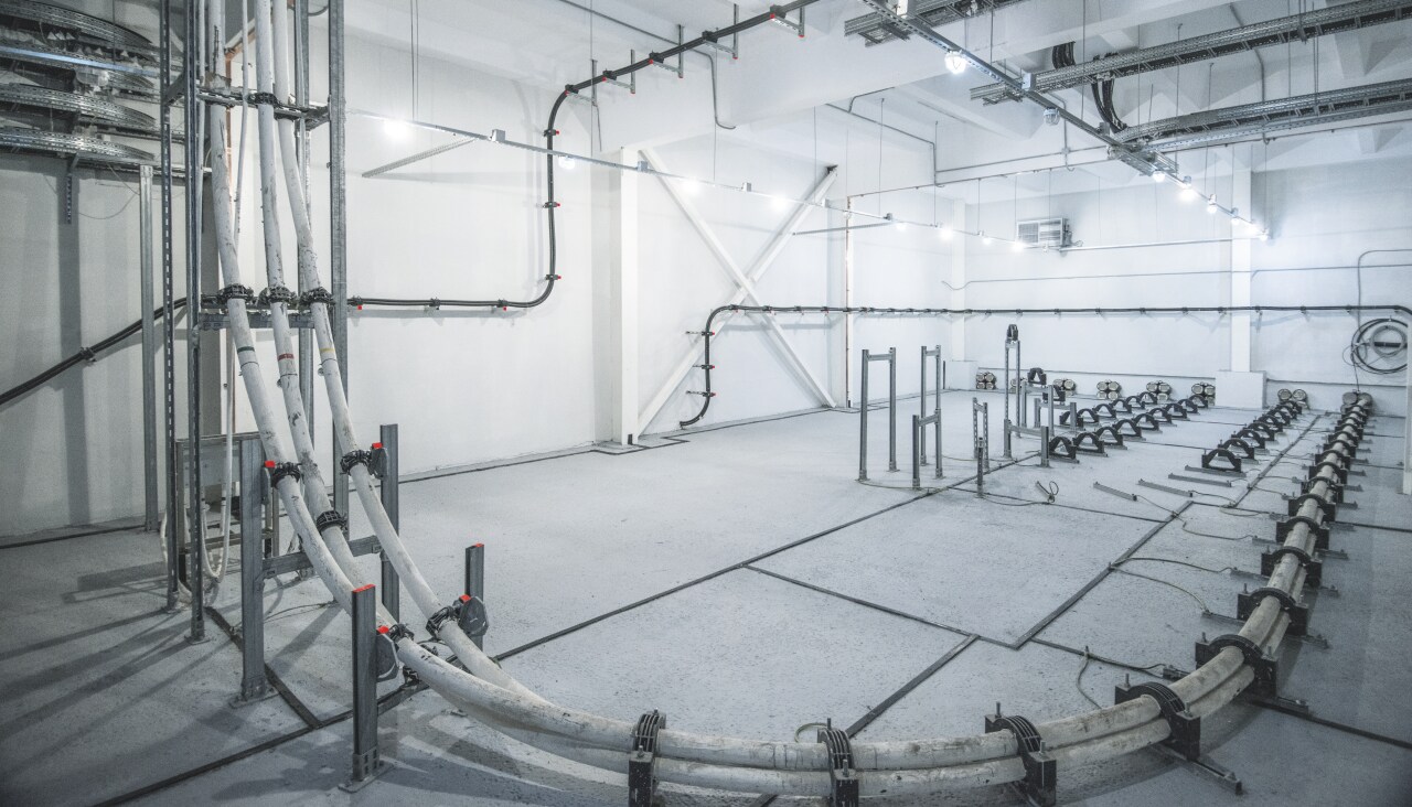 Metal support system leading pipes and cables inside of power plant room.