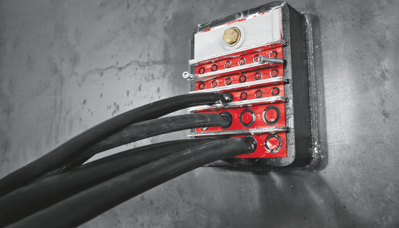 Cables going through a concrete wall bein sealed by Hilti passive firestop solution.