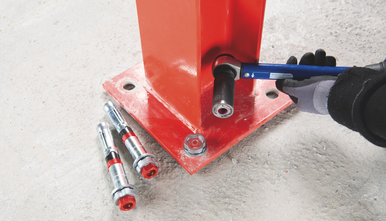 A man is installing mechanical anchor into a steel pilar.