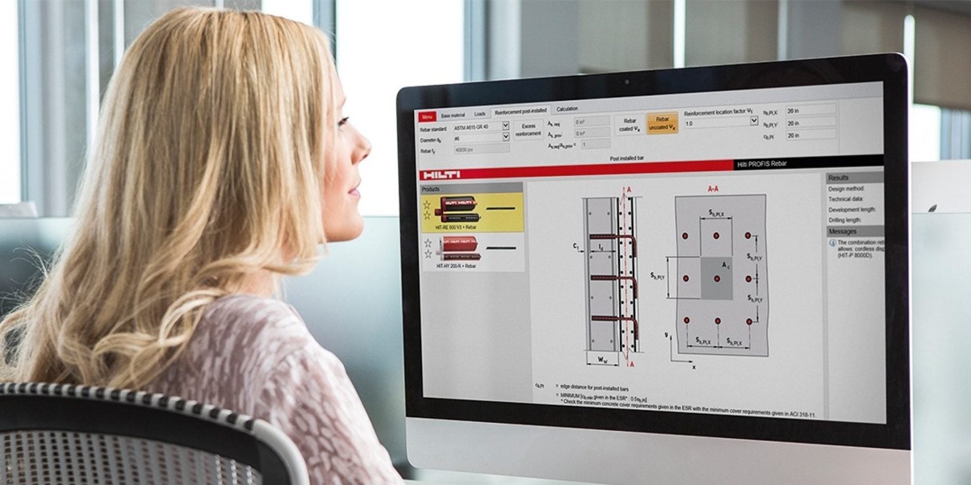 Man in an office using his laptop. On the screen is BIM Hilti construction software.