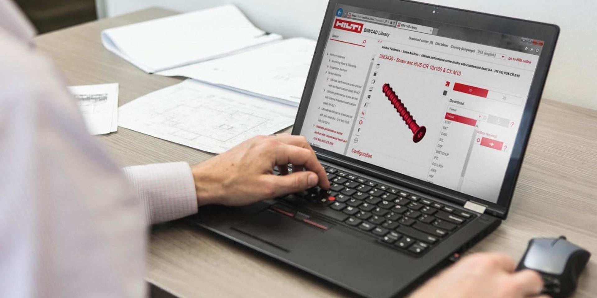 Man in an office using his laptop. On the screen is BIM Hilti construction software.