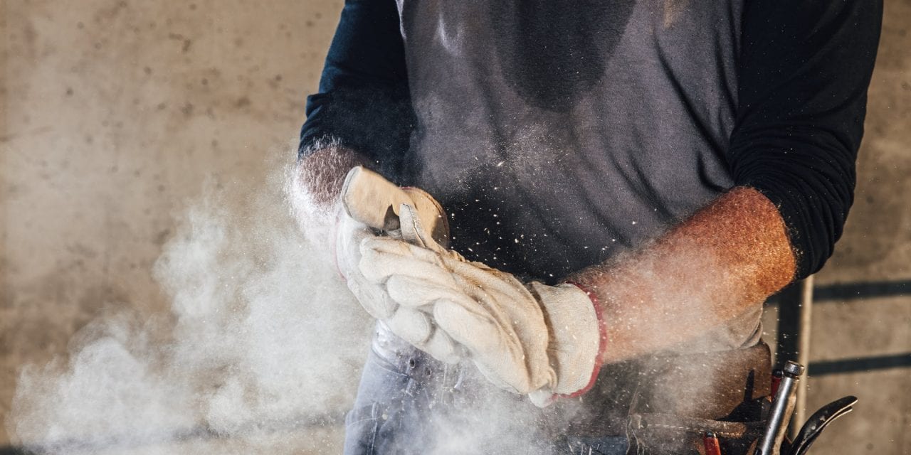 Man removing dust from his working gloves.