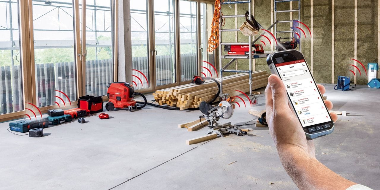 A man using ONTRACK! app on his phone. In The background are red Hilti tools communicating with the app.