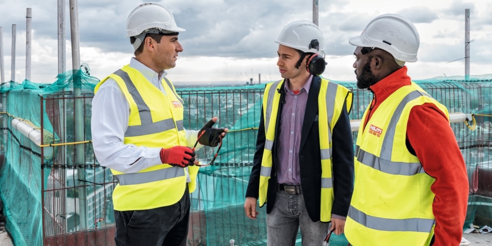 Group of men in yellow high vest discussing on construction site
