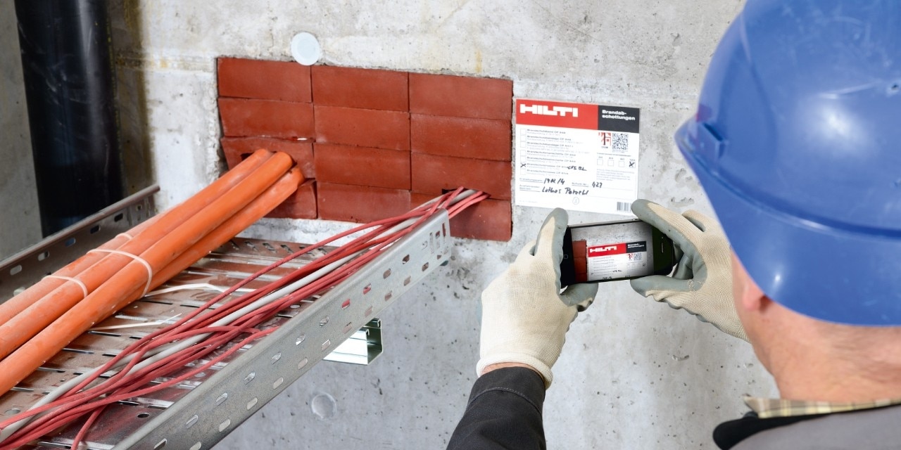 Hilti firestopping solotions, Man in a blue helmet takes picture of cables surrounded by firestops