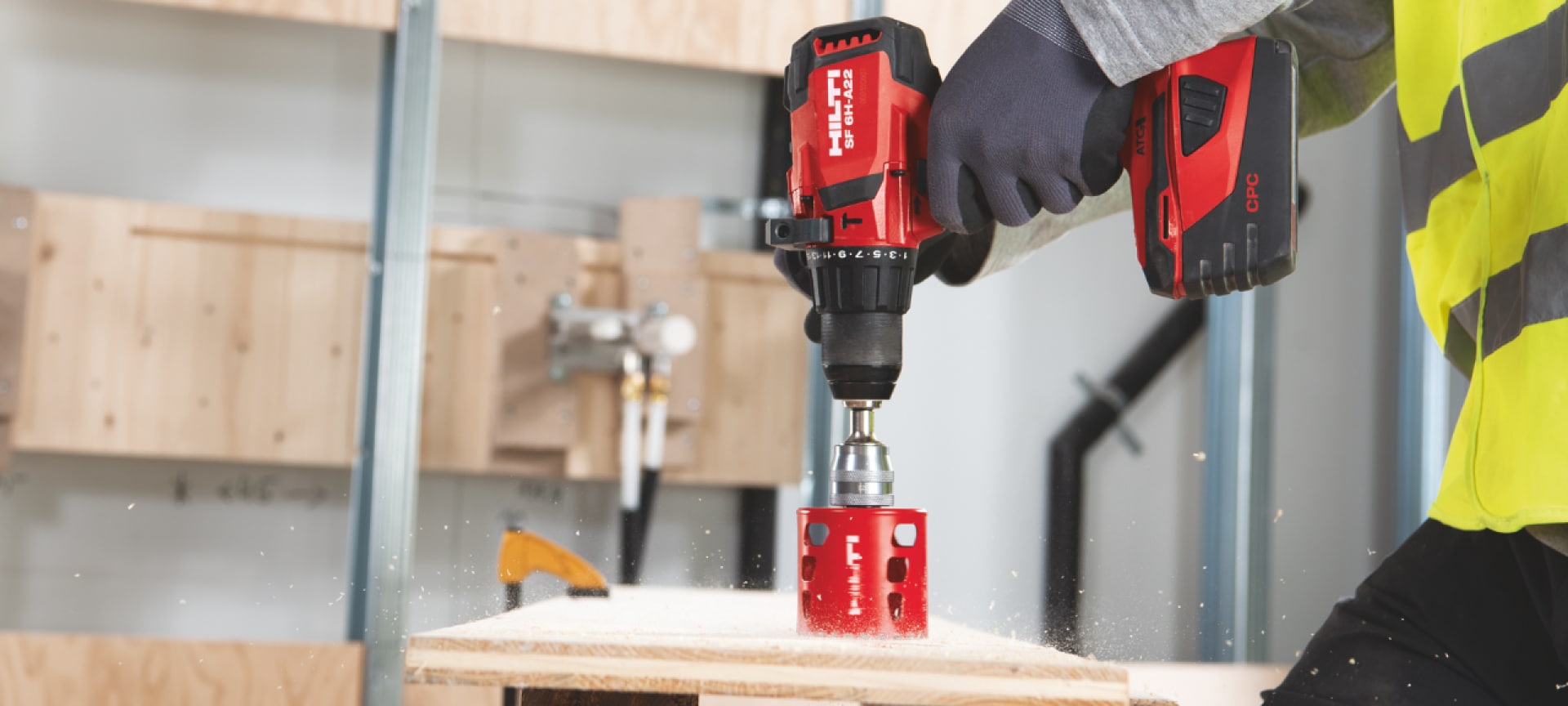 Man drilling a whole to timber with red Hilti drill driver with hole saw blade on it.