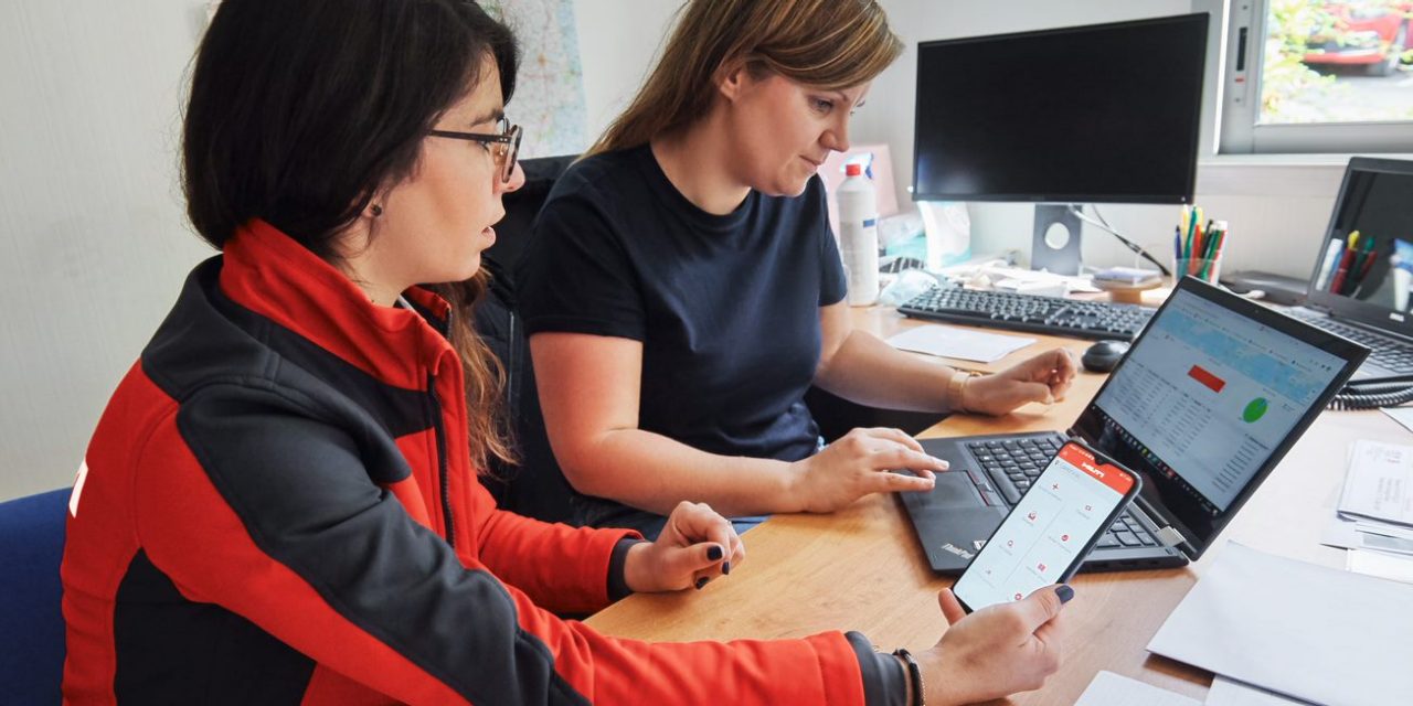 Two women, Hilti account manager and customer are using asset management software on smartphone and laptop in office. 