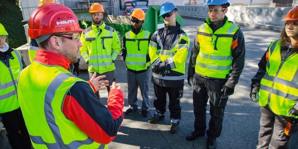 Group of construction workers listen to a Hilti Account manager on site. 