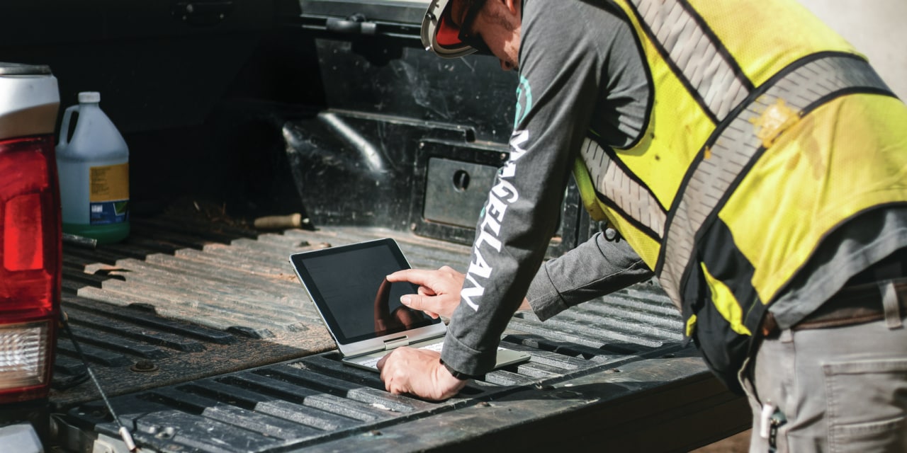 Construction worker using laptop on site. 