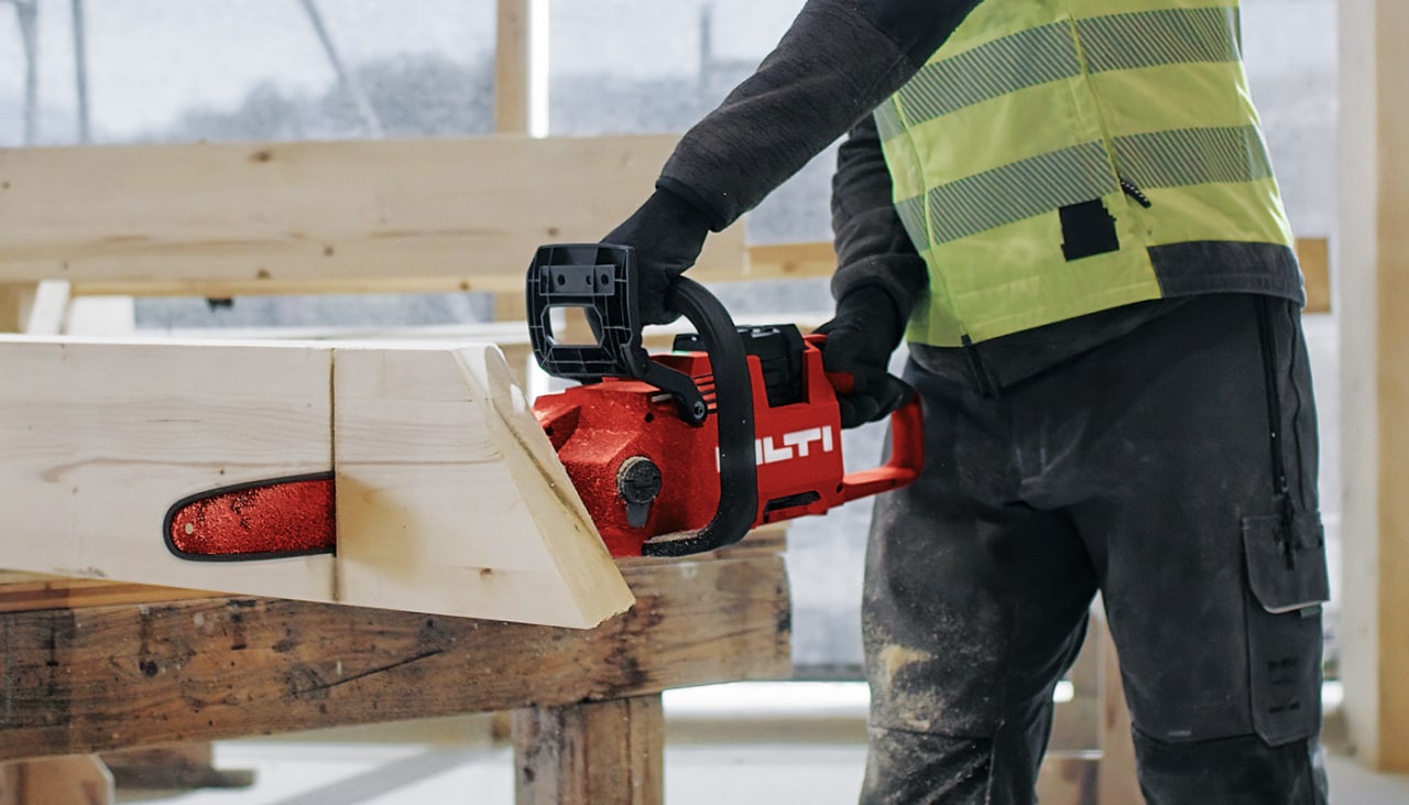 man using cordless chainsaw on a wood pile