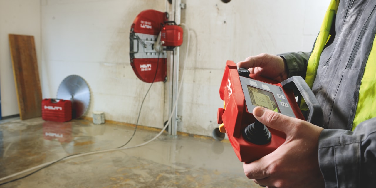 Man using remote controller of Hilti wall saw, which cuts the wall in the background.
