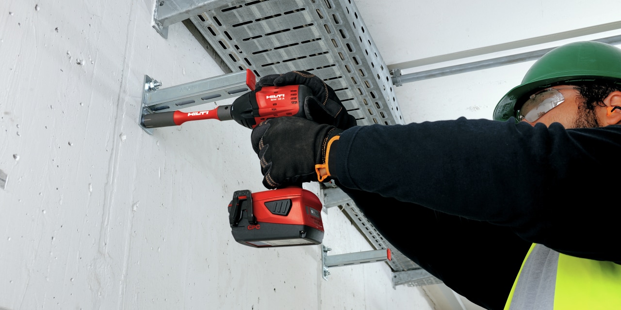 Man using red Hilti impact driver on site. 