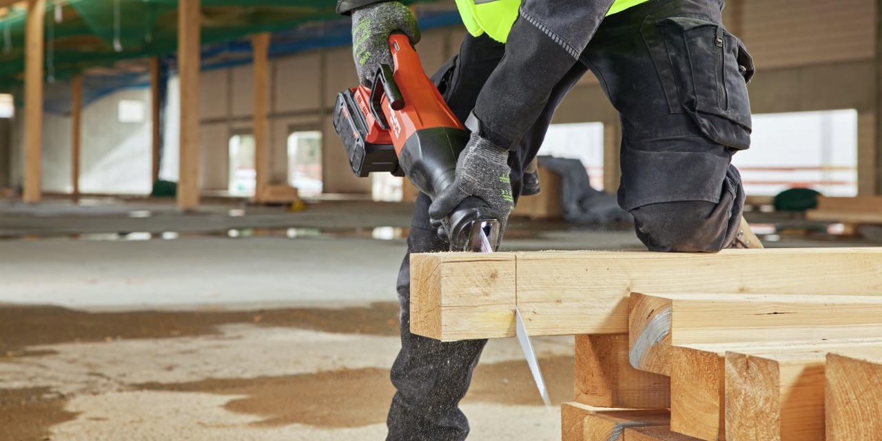 Construction worker using red Hilti reciprocating saw.