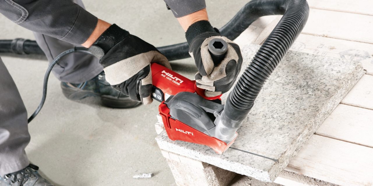 Man using red Hilti angle grinder to cut tiles.