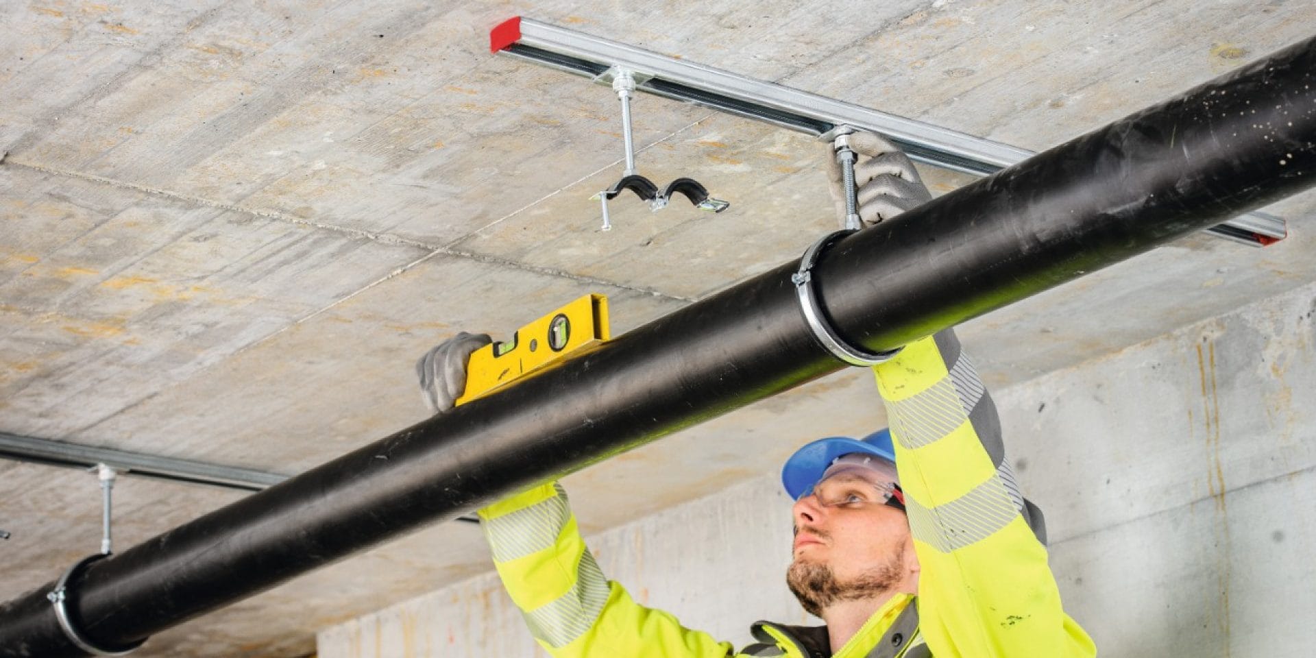 Hilti installation hardware being used to hang pipe from ceiling-mounted strut channels